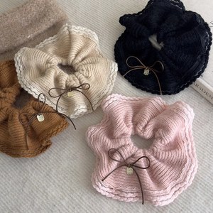 Detailed view of four knit scrunchies in beige, pink, black, and brown with bow charms