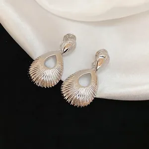 Silver hollow teardrop earrings with textured metal finish on white silk background