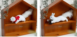 Detail of white plush squirrels with red bow and pine cone for Christmas decor
