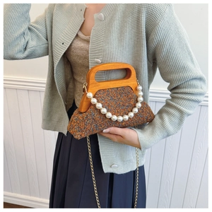 Detail of wool fabric texture with wooden handle and pearl chain on a brown handbag
