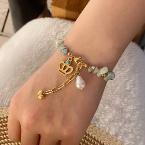Detail of natural stone beaded bracelet with crown charm and heart chain on wrist