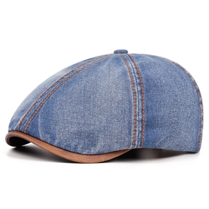 Close-up of vintage washed denim newsboy cap featuring detailed stitching and brown leather brim