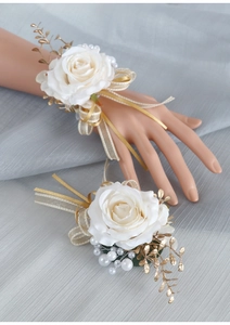 Dettaglio macro dei corsage da polso con rose bianche foglie dorate e perle fini
