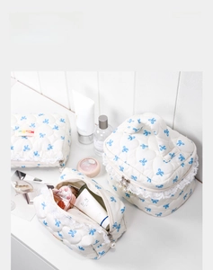Detailed close-up of quilted cosmetic bag with blue bow prints and lace trim edges