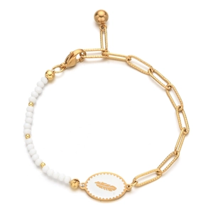 Detail of gold enamel feather charm bracelet with white beads and intricate metal textures