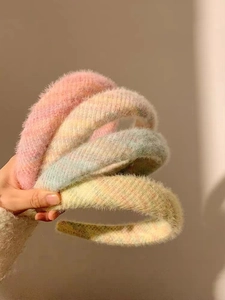 Gros plan de quatre serre-têtes en peluche douce en rose, jaune et bleu pastel