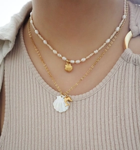 Detail of layered gold shell necklaces and pearl choker worn on a female neck