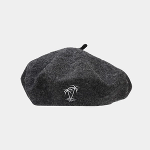 Close-up of a dark grey wool beret featuring detailed white coconut tree embroidery