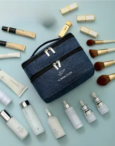 Blue double-layer cationic toiletry bag with travel accessories on a flat lay background