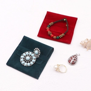 Flat lay of macaron-colored velvet jewelry pouches with bracelets, rings and charms