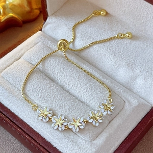 Detailed macro view of adjustable gold flower bracelet with zircon stars in a jewelry box