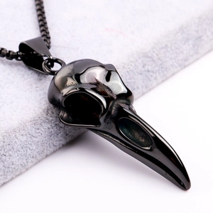 Macro shot of a polished black raven skull pendant on grey felt with high metal luster