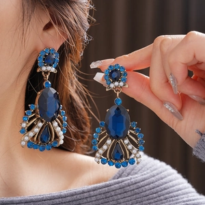 Detail of vintage style drop earrings with deep blue gemstones and pearls on model