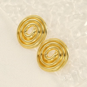 Dettaglio di orecchini a spirale dorati con cerchi concentrici e finitura minimalista
