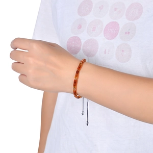 Detail of adjustable bohemian woven bracelet with amber resin beads and gold spacers