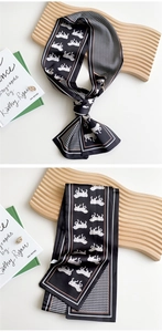 Detail of silk skinny scarf with horse print and houndstooth pattern tied on a wooden stand