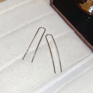 Makroaufnahme von minimalistischen silbernen U-Hakenohrringen auf weißem Samt-Tablett