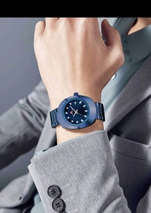 Detail of blue quartz watch with crystal indices and calendar display on male wrist