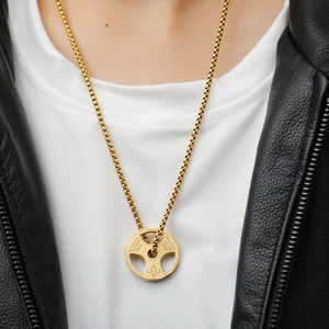 Golden barbell weight plate pendant necklace worn by a model in a black leather jacket