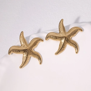 Boucles d'oreilles étoile de mer dorées avec texture martelée sur socle blanc minimal