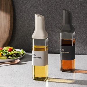 Leakproof glass oil dispenser set of 2 with black and white silicone grips on marble counter