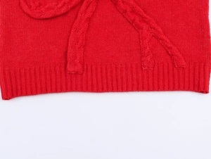 Macro view of red cable-knit texture and ribbed hem detail on a stylish casual sweater