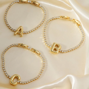 Gold tennis bracelet with cubic zirconia and alphabet letter pendants on silk
