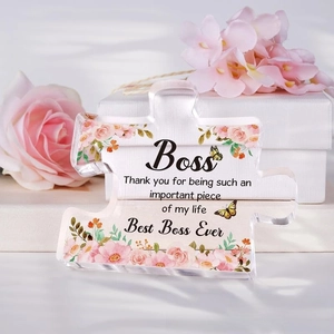 Macro shot of puzzle-shaped acrylic plaque with floral prints and Best Boss Ever message