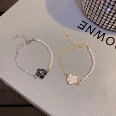 Detail view of pearl bracelets with black and white camellia charms and zirconia accents