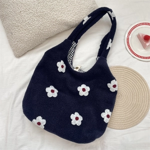 Detailed macro view of fuzzy navy blue underarm tote bag with white embroidered flowers