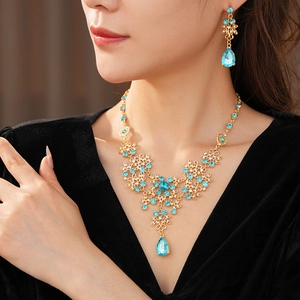 Detailed view of vintage gold necklace and blue rhinestone flower earrings on model