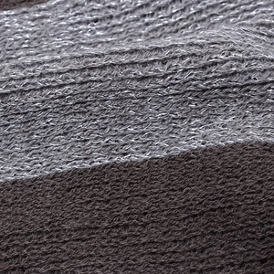 Close-up of knit fabric showing gray metallic threads and dark brown striped texture