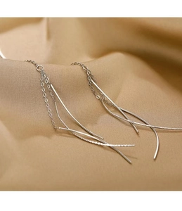 Close-up of elegant long silver tassel drop earrings on soft white textured fabric