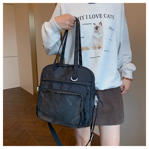 Detail view of the black canvas ita bag with mesh front pocket worn over the shoulder