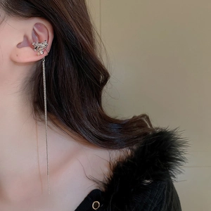 Gros plan d'un ear cuff papillon argenté avec longue chaîne à pampilles et zircons