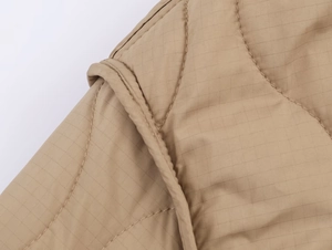 Détail macro du tissu matelassé kaki avec motif quadrillé ripstop et double surpiqûre