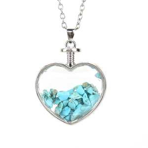 Macro detail of heart-shaped crystal pendant filled with turquoise stones on silver chain