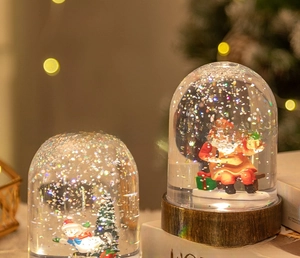 Close-up of LED glowing Christmas snow globe with Santa Claus and sparkling glitter inside
