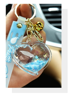 Close-up detail of a heart-shaped acrylic quicksand keychain with shiny blue glitter.