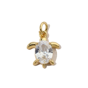 Detailed view of turtle-shaped gold pendant with inlaid zircon and a polished metal base