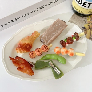 Flat lay of 8 realistic 3D resin food hair clips including chicken wings and ribs