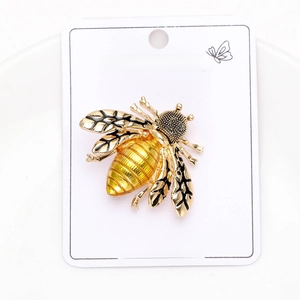 Detailed view of a gold bee brooch with black enamel wings on a jewelry card