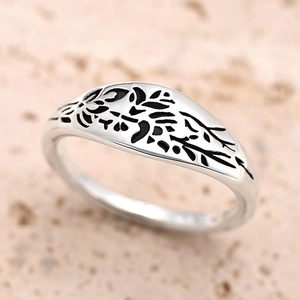 Close-up of vintage silver metal ring featuring intricate black floral branch engraving