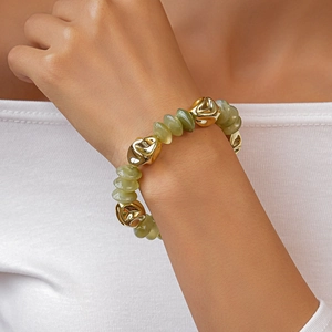 Detail of beaded bracelet with translucent yellow-green and irregular gold metal beads
