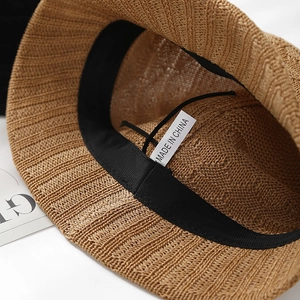 Close-up of hollow knit bucket hat with inner sweatband, adjustable drawstring and tag