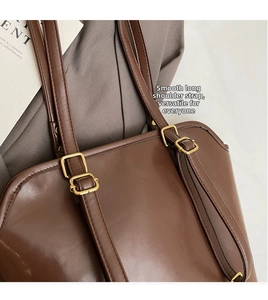 Detail of adjustable long shoulder strap and gold hardware on dark brown leather tote bag