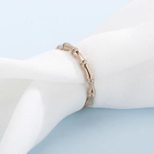 Detailed view of rose gold bamboo design ring on soft white fabric background