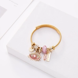 Bracelet câble doré avec breloques œil de fatima et perles roses sur décor minimaliste