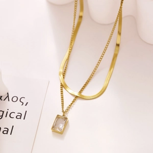 Detail of double-layer gold necklace featuring flat snake chain and zircon heart pendant