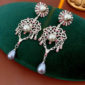 Détail de boucles d'oreilles vintage avec perles grises et cristaux roses sur velours